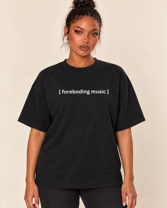 [Closed Captions] Foreboding Music - Unisex Oversized Boxy Tee — Black on Treattees studio model, matching actual CustomCat print placement